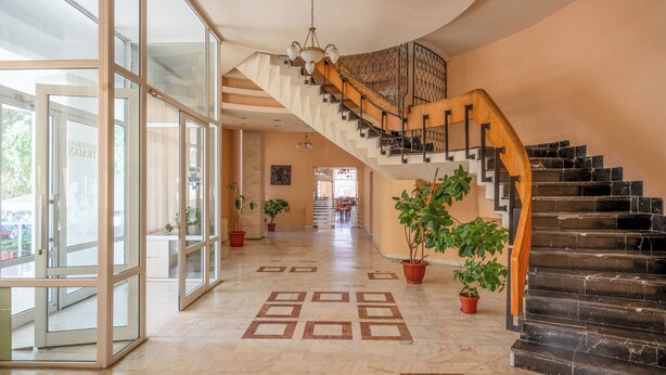 A spacious foyer with a grand staircase, potted plants, and a patterned floor. - Traian Braila (Braila)