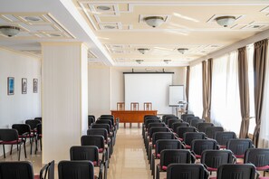 A conference room with rows of chairs, a podium, a projector screen, and a whiteboard. - Traian Braila (Braila)