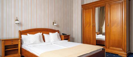 Une chambre d’hôtel avec un lit en bois, une armoire, une table de chevet et un miroir.