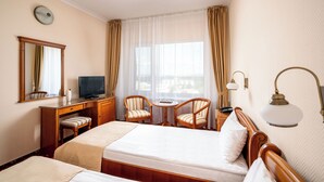 A hotel room with a bed, a desk, a television, two chairs, a lamp, and a window with curtains. - Traian Braila (Braila)