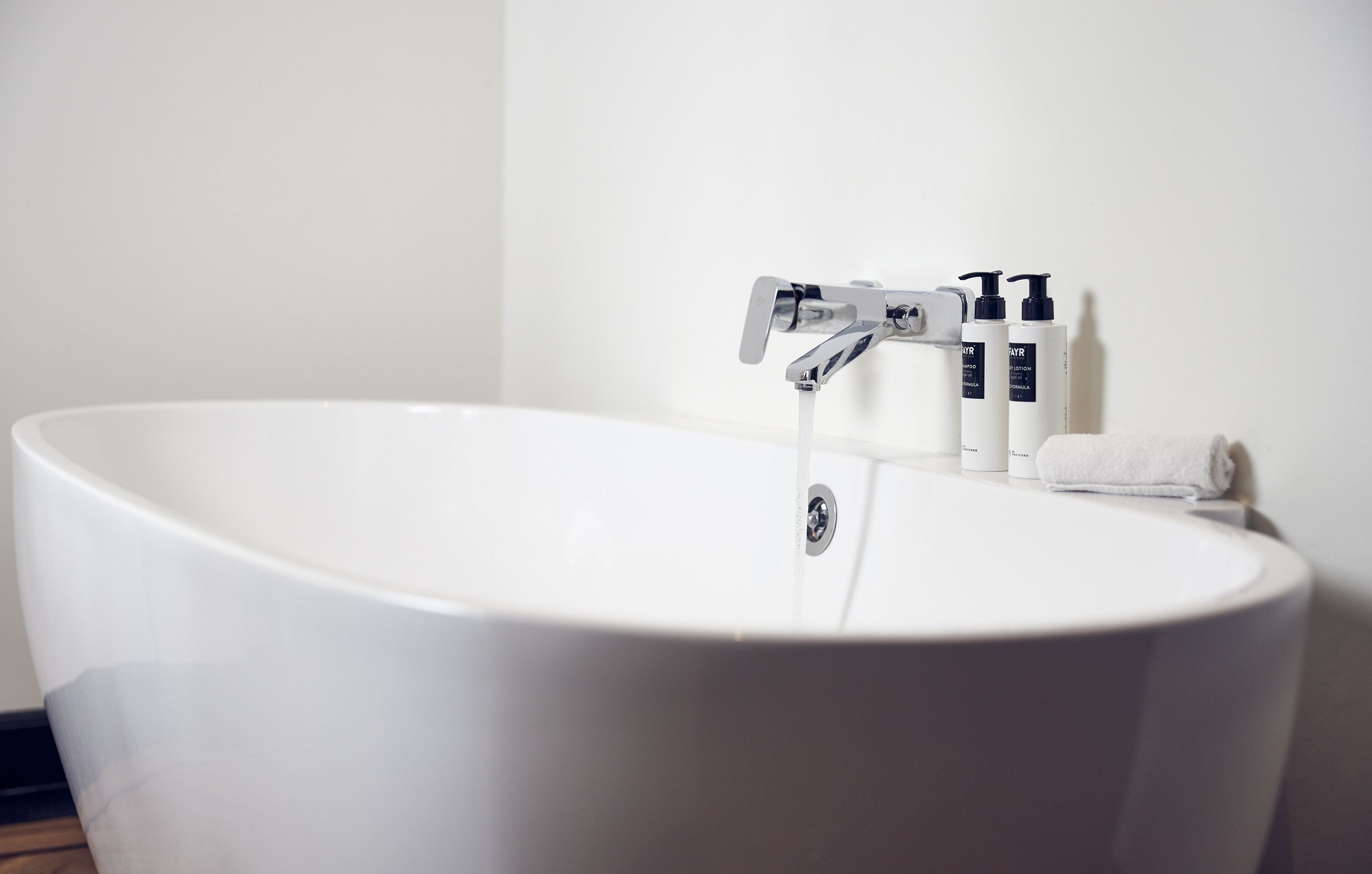 Un baño moderno con una bañera independiente, un grifo y artículos de aseo a un lado.
