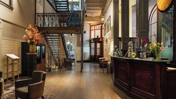 Un interior espacioso con suelo de madera, una escalera, una zona de bar y un área de estar.