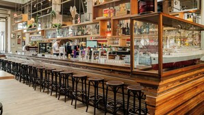 Zona de bar con estantes de madera, taburetes y un gran modelo de barco.