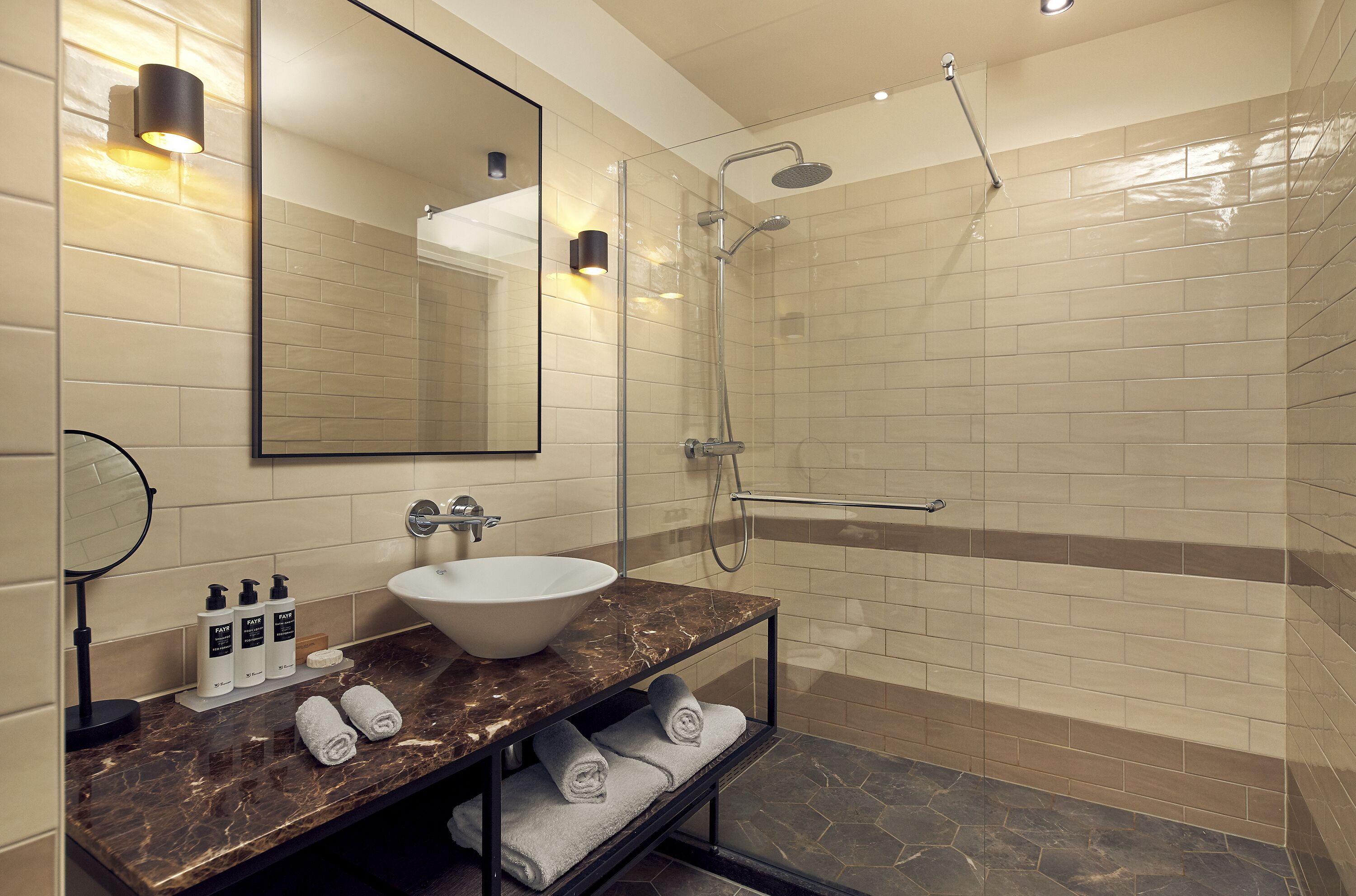 A modern bathroom with a glass-enclosed shower, a marble sink, and a large mirror.
