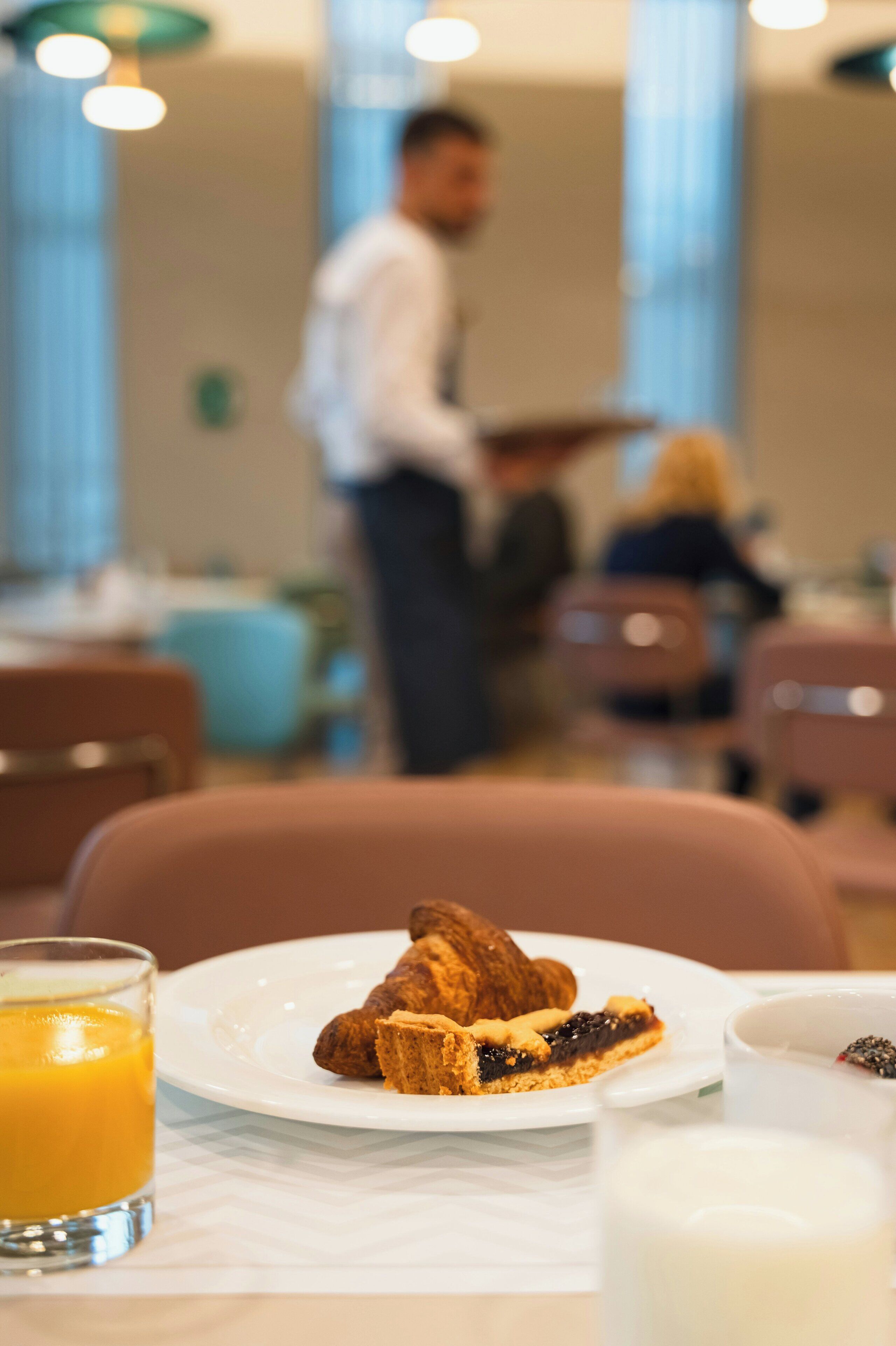 A breakfast setting with croissants and a glass of orange juice on a table.