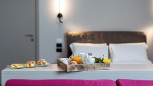 A neatly made breakfast tray on a bed with a white headboard, a bedside table, and a wall-mounted light.