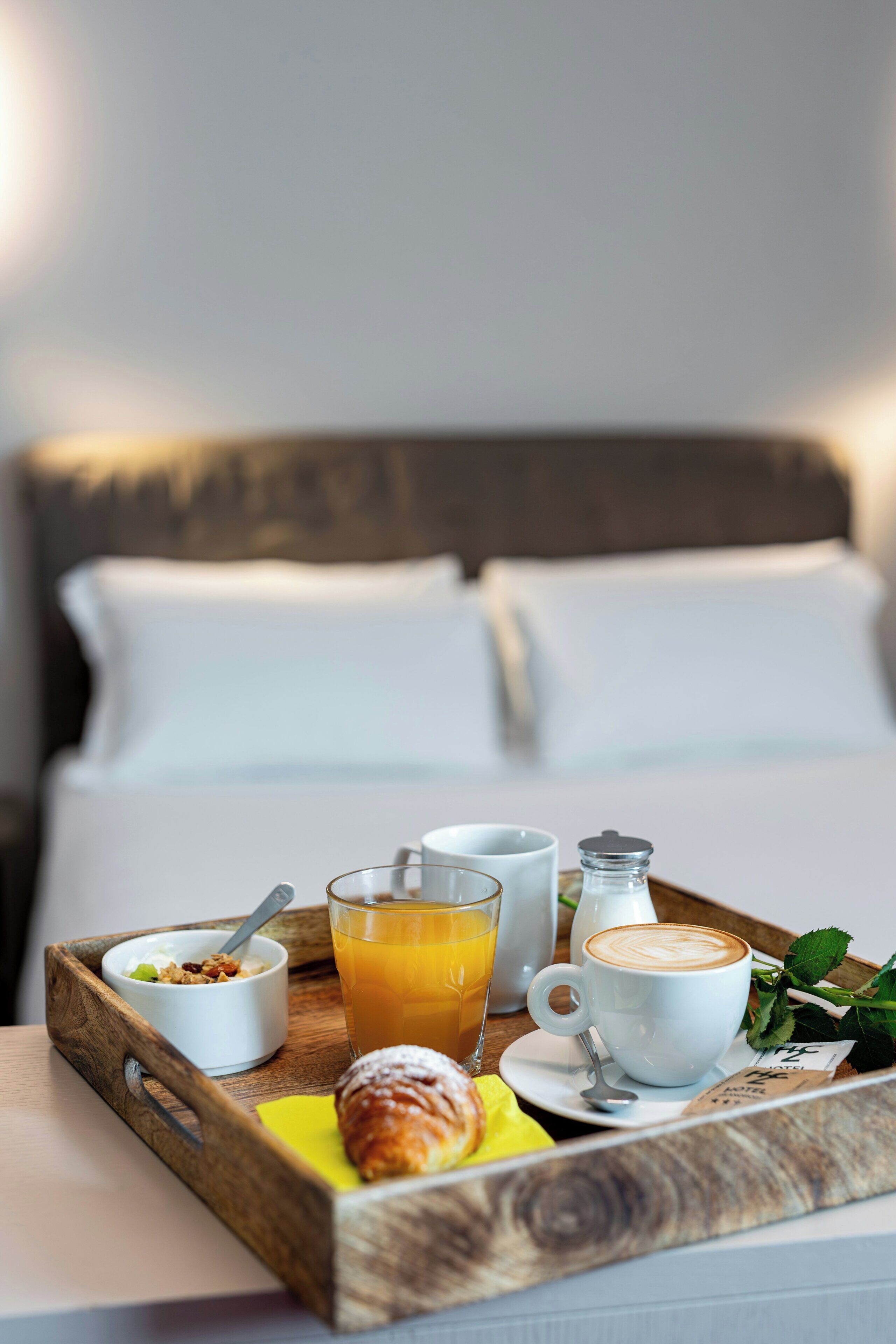 Ein Frühstücksbrett mit einem Croissant, Orangensaft, Kaffee und einer kleinen Schale Müsli.