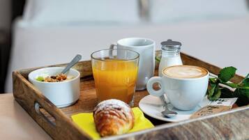 Ein Frühstücksbrett mit einem Croissant, Orangensaft, Kaffee und einer kleinen Schale Müsli.