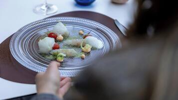 Une table à manger avec une assiette de nourriture, un verre d’eau et un vase bleu.