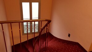 A staircase with a wooden handrail and a window with frosted glass.
