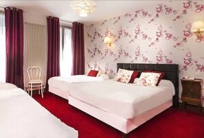 A hotel room with two beds, a red carpet, a chair, and a wall with floral wallpaper. - Hotel Le Clos d'Alésia (Paris)