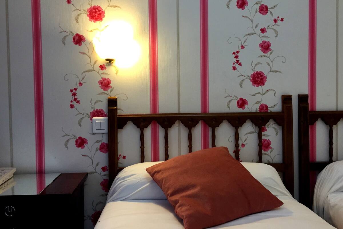 A bedroom with a bed, a nightstand, and a wall-mounted light fixture.