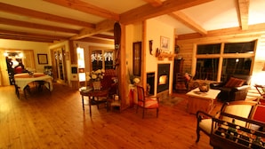 A spacious living area with wooden floors and furniture, a fireplace, and a dining area with a table and chairs. - Escale du Nord (Mont-Tremblant)