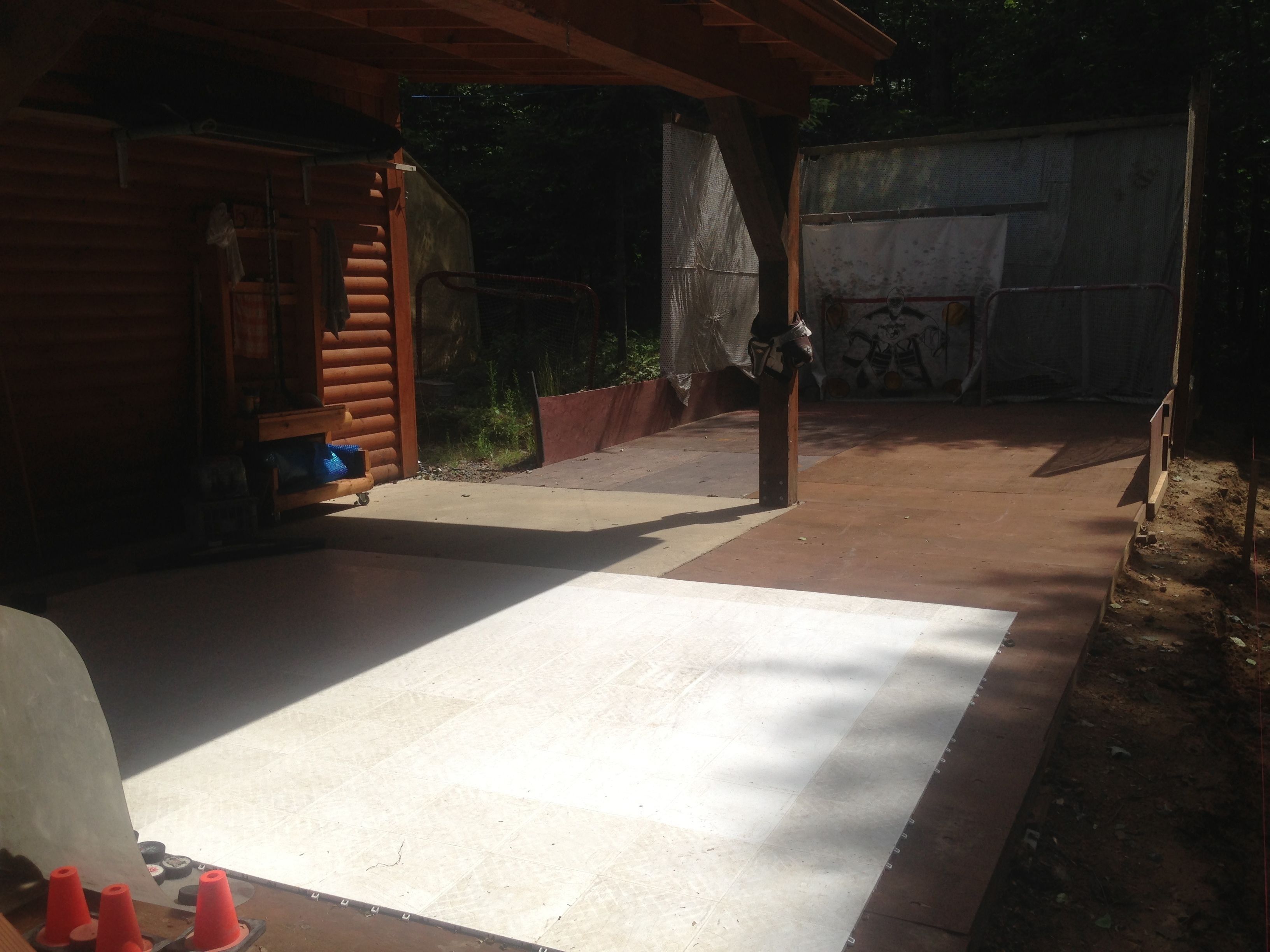 Un patio couvert doté d’un sol en béton, de poutres en bois et d’un portail en métal.