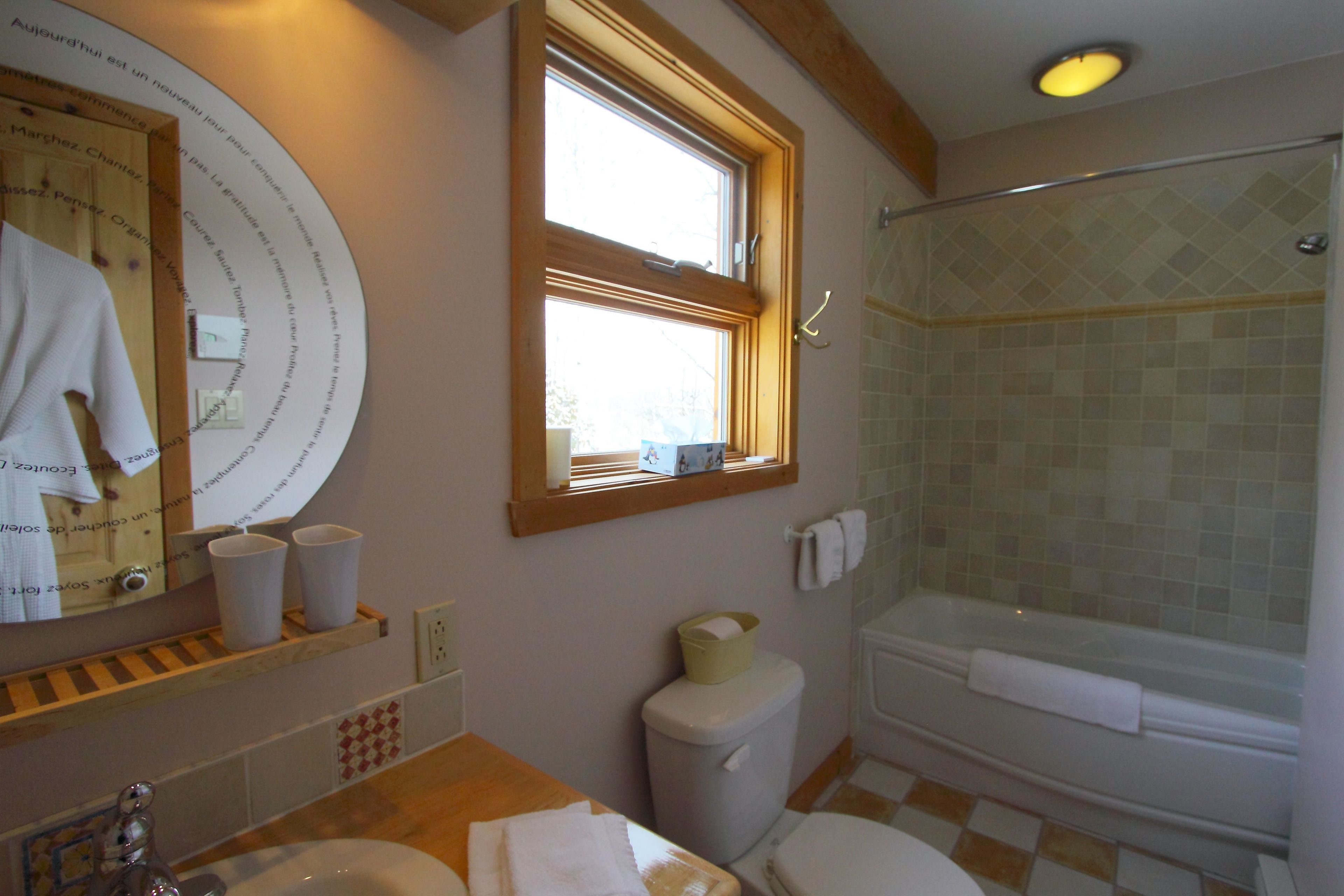 A bathroom with a bathtub, toilet, sink, and a window.