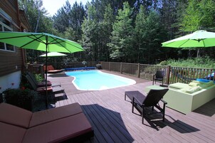 Una piscina al aire libre, sombrillas, sillones reclinables de piscina