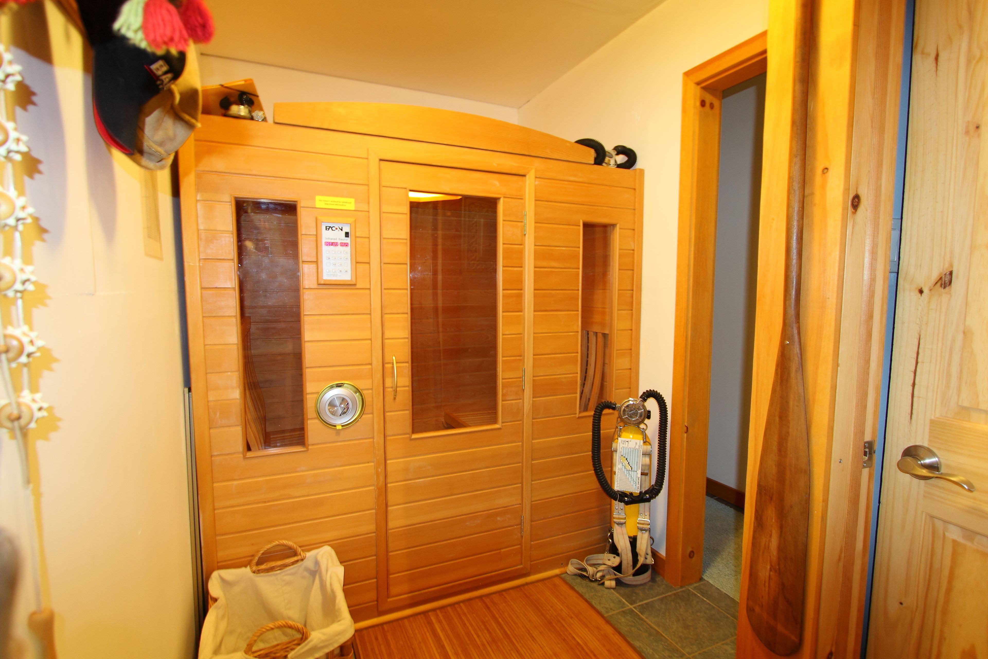Un sauna de madera con puerta, un perchero y un equipo de sauna.