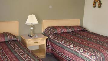 A bedroom with two beds, a nightstand, a lamp, and a remote control.