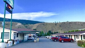 Un motel con varias habitaciones, una gasolinera y montañas al fondo.