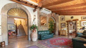 Amplia sala de estar con techo de madera, un sofá de cuero verde, un tapete grande y una escalera que conduce a otra habitación.