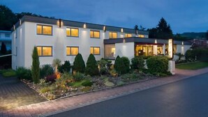Ett modernt hotell i två våningar med en välskött trädgård och en asfalterad uppfart.