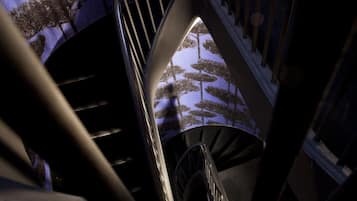 A spiral staircase with a view of trees through a window.