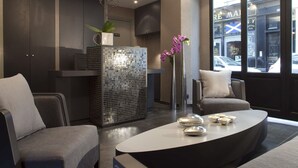 A modern interior with a sofa, a coffee table, a decorative mirror, and a view of the street outside.
