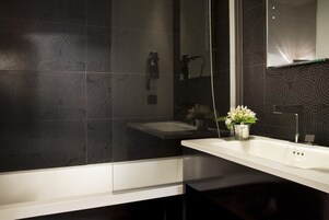 Een moderne badkamer met een grote spiegel, een witte wasbak en een douche.