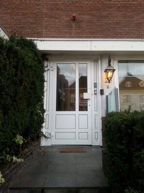 A white door with a glass panel, a small step leading up to it, and a brown mat at the entrance. - Oranje Hotel Sittard (Sittard)