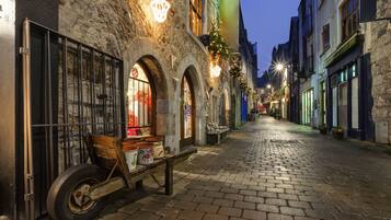 A cobblestone street lined with historic buildings, some with visible storefronts and others with closed shutters.