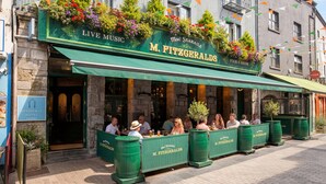 Un restaurant doté d’une terrasse, d’un auvent vert et de jardinières au-dessus de l’entrée.