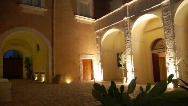 A building with a courtyard, stone arches, and a well-lit entrance. - Hotel Palazzo Gambuzza - Ispica (Ispica)