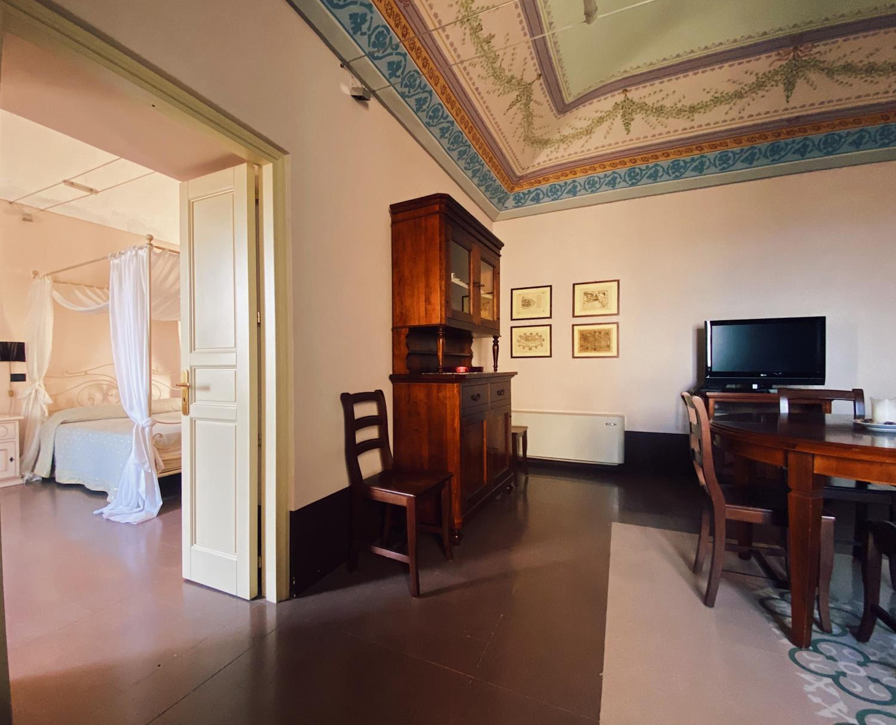 A room with a bed, a wooden cabinet, a television, and framed pictures on the wall.