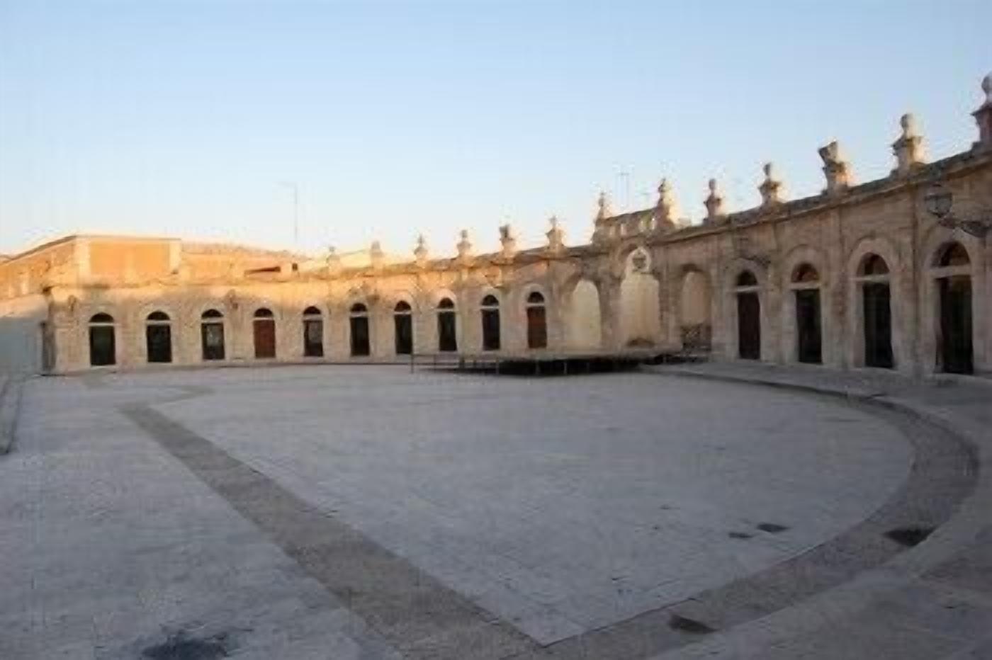 A courtyard with a central open space surrounded by arched doorways and a building facade with decorative elements.