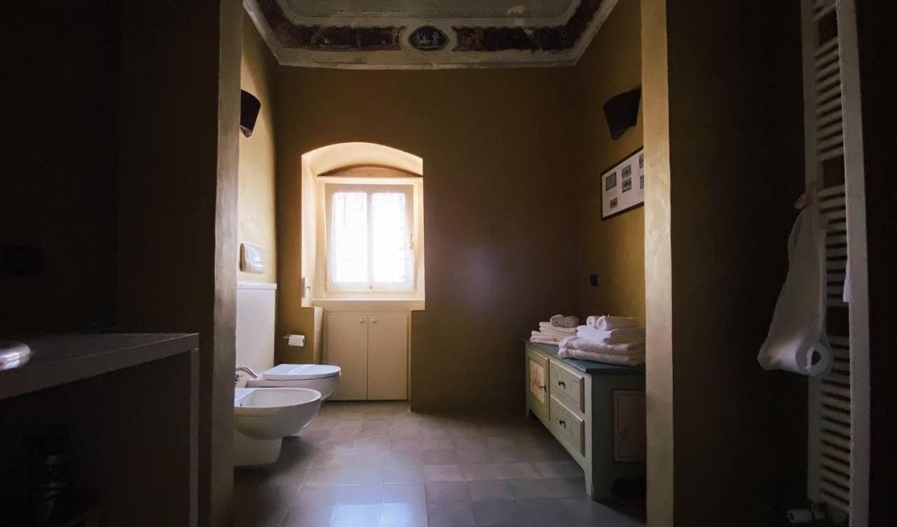 Een kleine badkamer met toilet, wastafel en een raam voor natuurlijk licht.