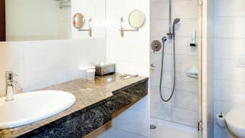 Ein modernes Badezimmer mit Marmorplatte, Waschbecken, Spiegel, Duschbrausehandstück und Toilette.