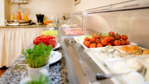 Un bufé con diversas opciones de comida, incluyendo verduras cortadas, tomates cherry y pasteles.