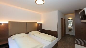 A hotel room with two beds, a TV, and a mirror.