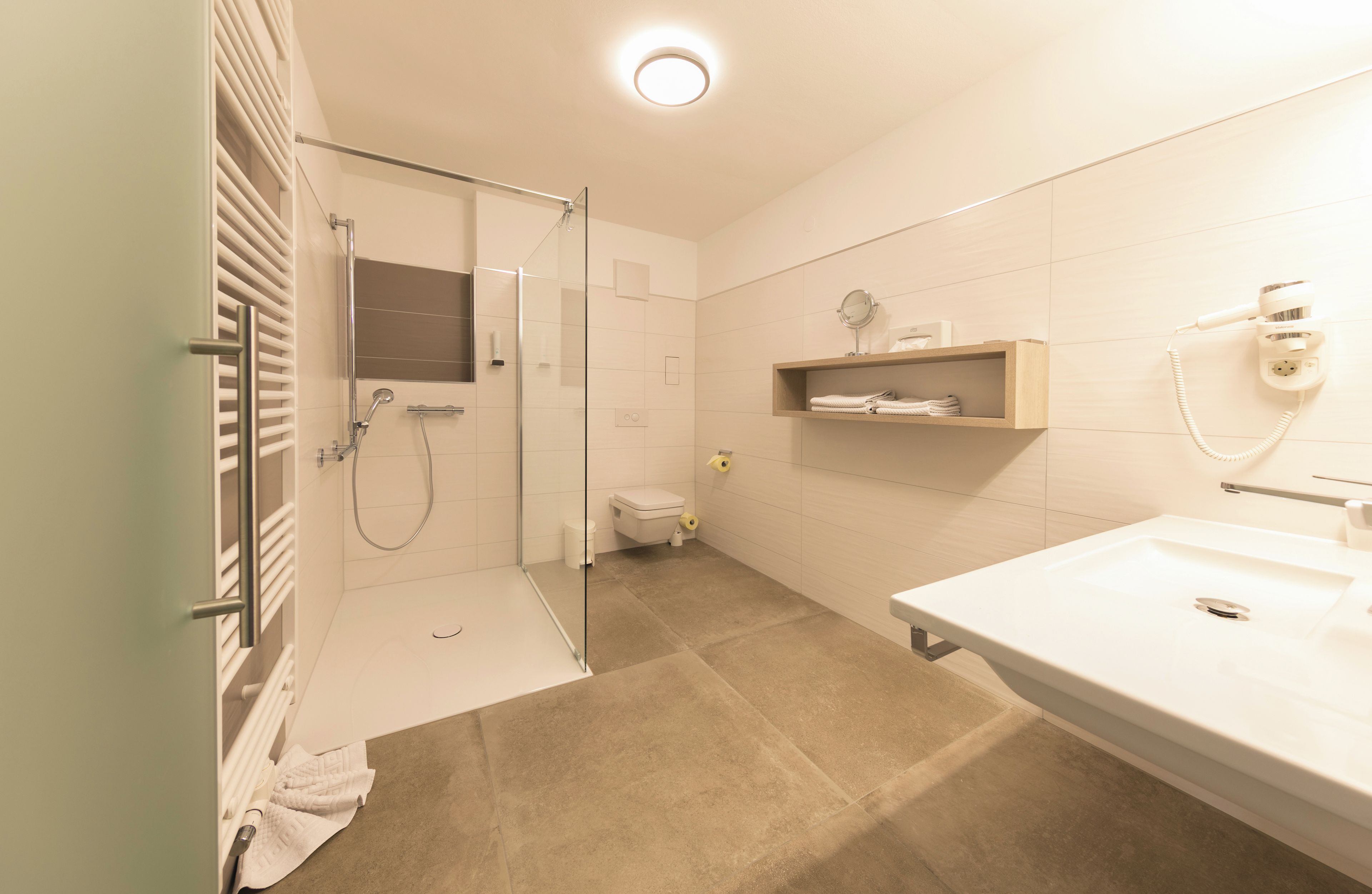 A modern bathroom with a glass-enclosed shower, a white sink, and a towel rack.