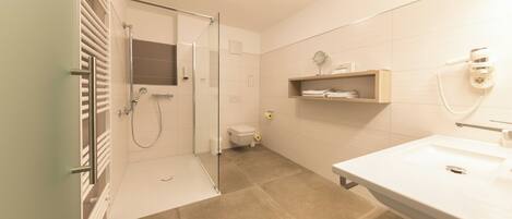 Een moderne badkamer met een douche met glazen wand, een witte wastafel en een handdoekrek.