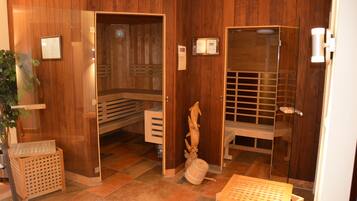 Área de spa com piso de madeira, sauna, mesa de massagem e um pequeno banco de madeira.