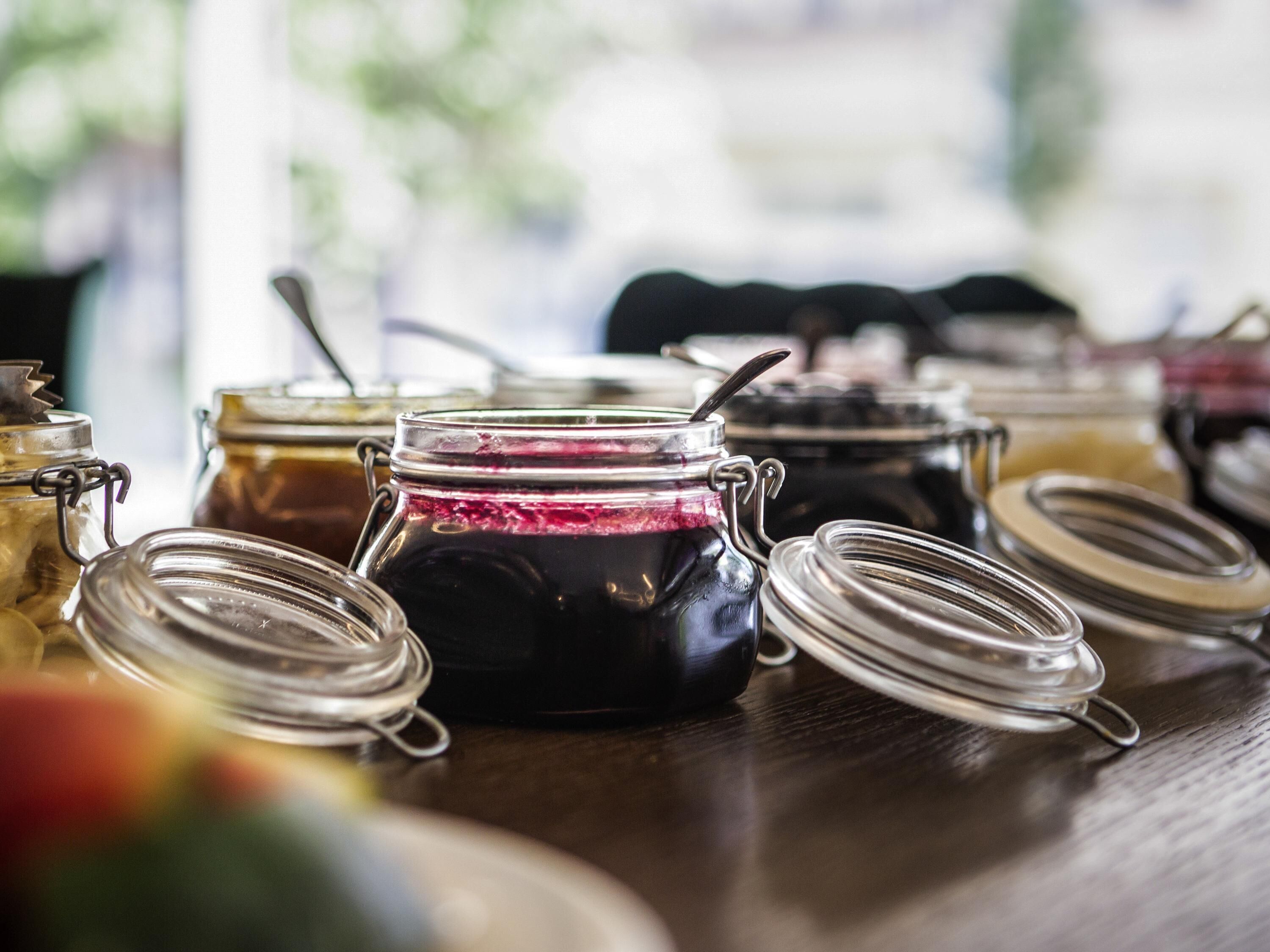 A variety of glass jars with metal lids, likely containing preserves or pickles, on a wooden surface.