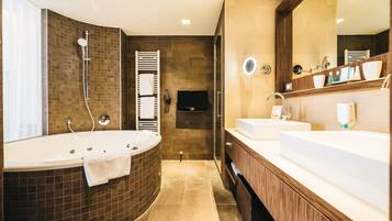 A modern bathroom with a bathtub, two sinks, a vanity, and a mirror.