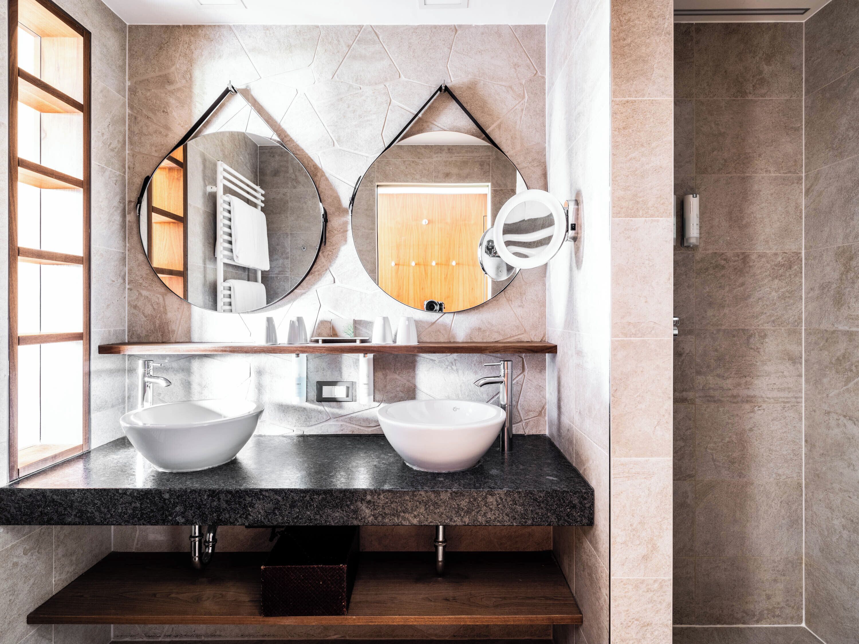 Ein modernes Badezimmer mit zwei Waschbecken, einem großen Spiegel und einer Holztür.