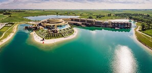 Un gran hotel con un edificio central circular, varias alas y una masa de agua circundante.