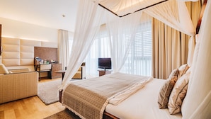 Una habitación de hotel moderna con una cama grande, un sofá, un escritorio y un televisor.