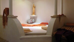 Un dormitorio con una cama, una estatua y una mesita.