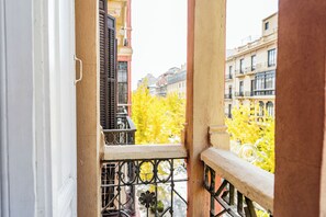 A balcony with a wrought iron railing, a view of yellow trees, and buildings in the background. - Hostal Sonia (Granada)