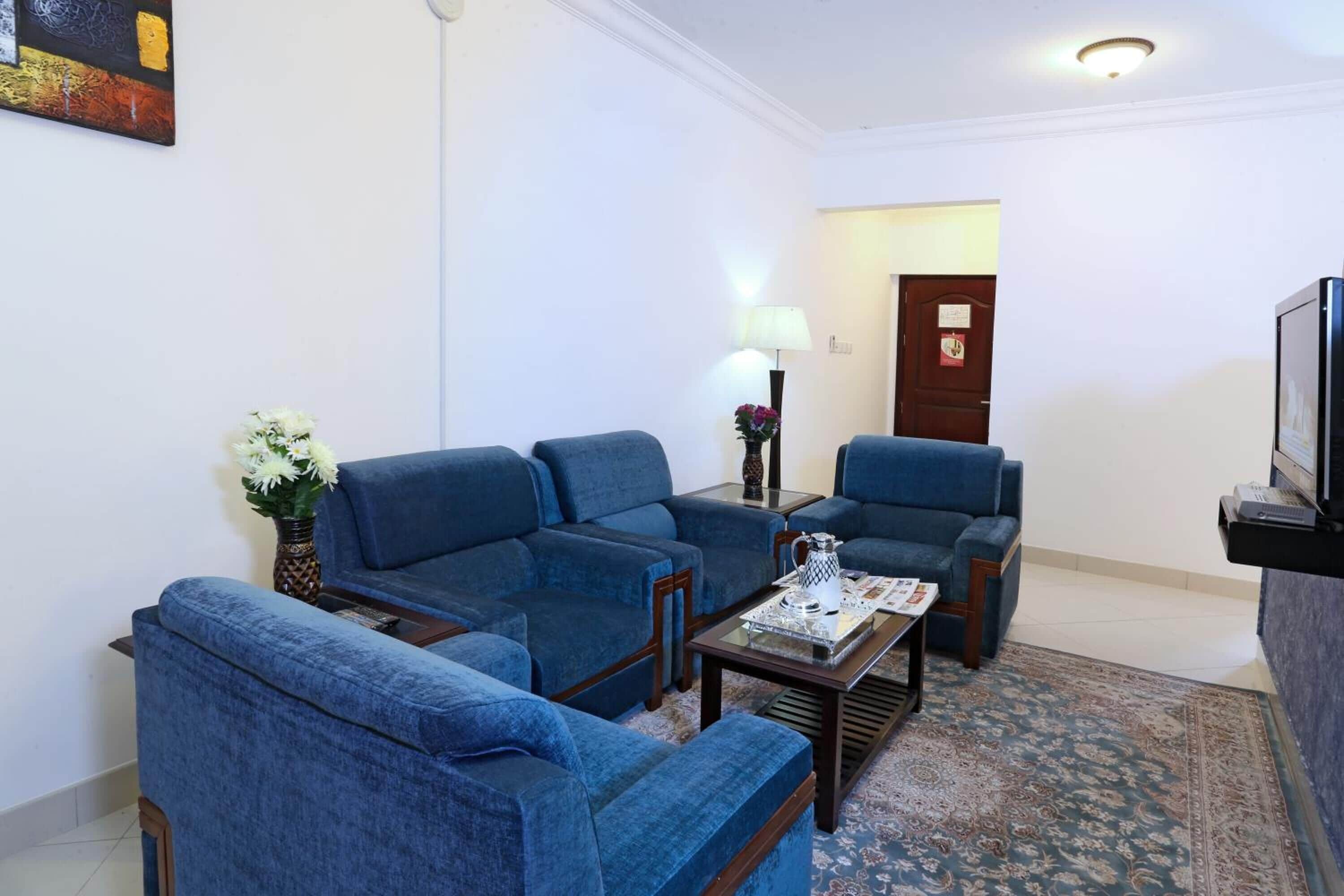 Ein Wohnzimmer mit blauen Sofas, einem Couchtisch und einem Fernseher.