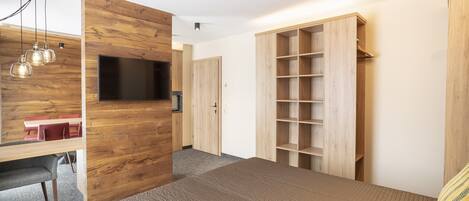 A modern bedroom with a wooden wall, a bed, a TV, and a wardrobe.